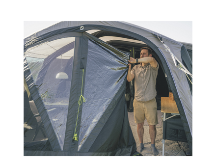 man rolling clossed a grey and black tent front door 