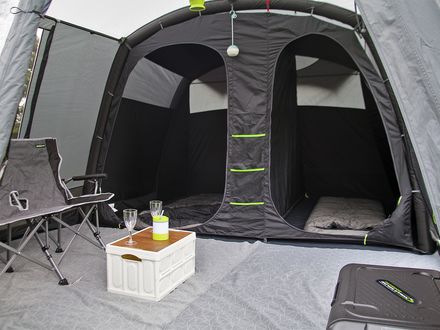Camping tent interior with chairs, table, and supplies inside a gray tent.