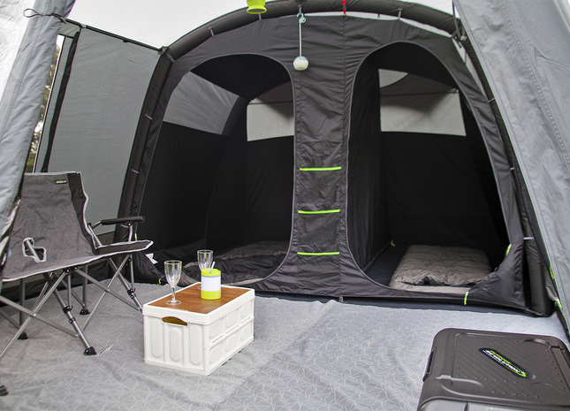 Camping tent interior with chairs, table, and supplies inside a gray tent.