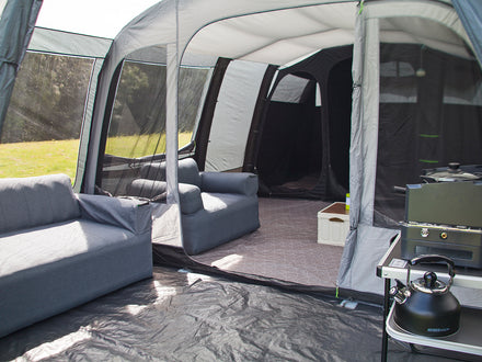 Camping setup with inflatable tent, furniture, and outdoor equipment.