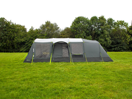 Large camping tent on grass with trees in the background
