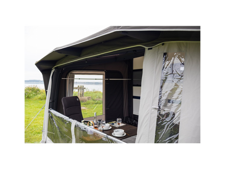 Camper van awning with interior view showing a table set for a meal with a scenic background.
