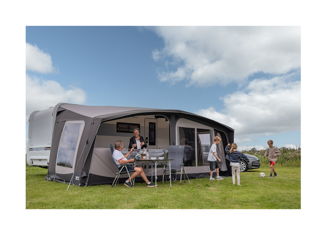 Family enjoying time outdoors next to a caravan with an awning on a grassy area.