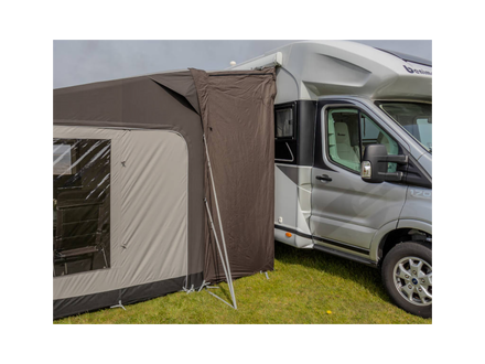 Camper van with an extended brown awning on a grassy area