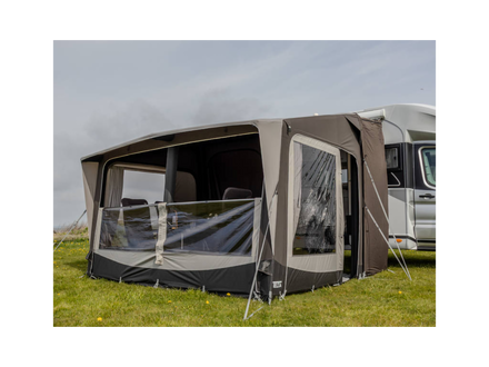 Camping trailer with an attached awning on a grassy field.