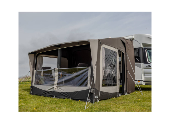Camping trailer with an attached awning on a grassy field.