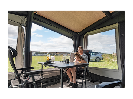 Person sitting at a table inside an awning with a scenic view outside