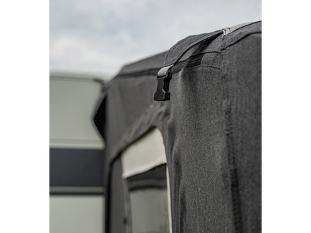 Close-up of a gray awning attached to a building with a cloudy sky in the background.