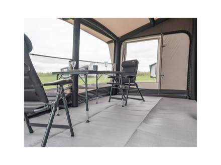 Awning interior with table, chairs, and view of green field