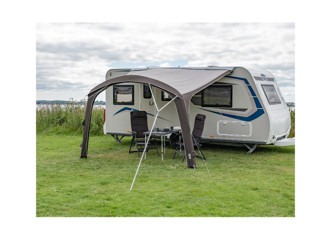 Caravan with an extended awning in a grassy outdoor setting
