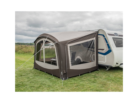 Caravan with an attached awning on a grassy field under a cloudy sky