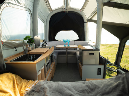 Interior of a trailer tent with kitchen setup and outdoor view