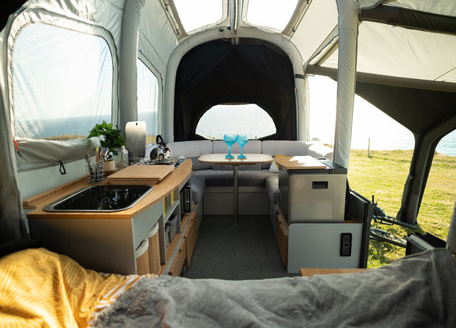 Interior of a trailer tent with kitchen setup and outdoor view