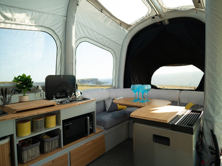 Interior of a trailer tent with kitchenette and seating area