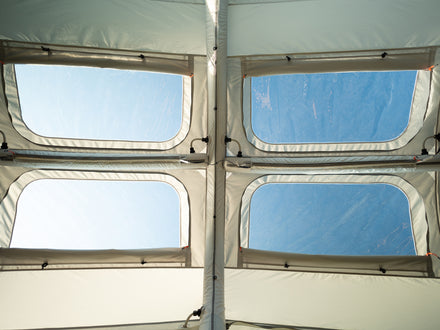 Tent interior with four square windows and a blue sky outside
