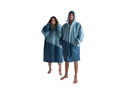 Two models wearing matching color-blocked hooded changing robes, one in a light blue and dark teal-blue colorway and the other in a pale blue and medium teal-blue colorway, set against a solid white background.