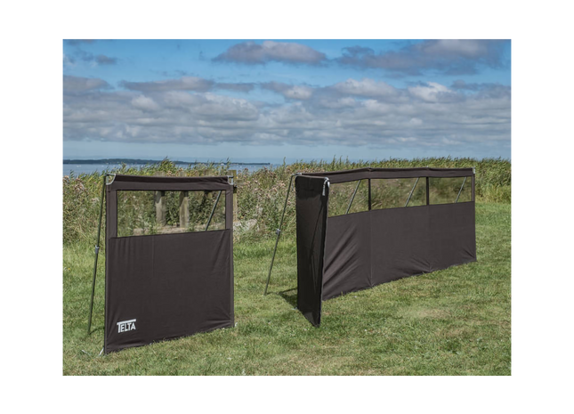 Two black outdoor privacy screens on grass with a cloudy sky background