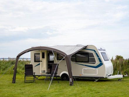 sun canopy attached to a caravan on a grassy area
