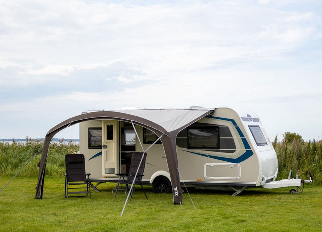 sun canopy attached to a caravan on a grassy area

