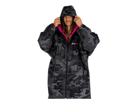 A model wearing a dark gray and black camouflage hooded dryrobe with a bright pink lining and a visible 'dryrobe' logo on the chest, set against a plain white background.