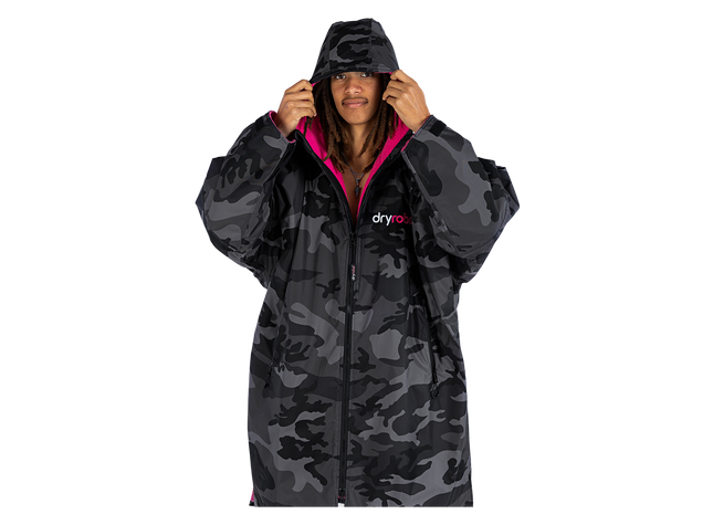 A model wearing a dark gray and black camouflage hooded dryrobe with a bright pink lining and a visible 'dryrobe' logo on the chest, set against a plain white background.